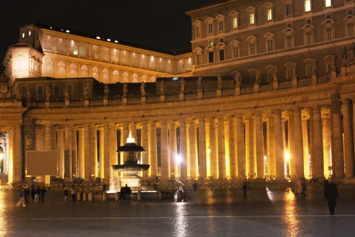 Night view of St. Peter's Square: one of the fountains and the columns surrounding the square