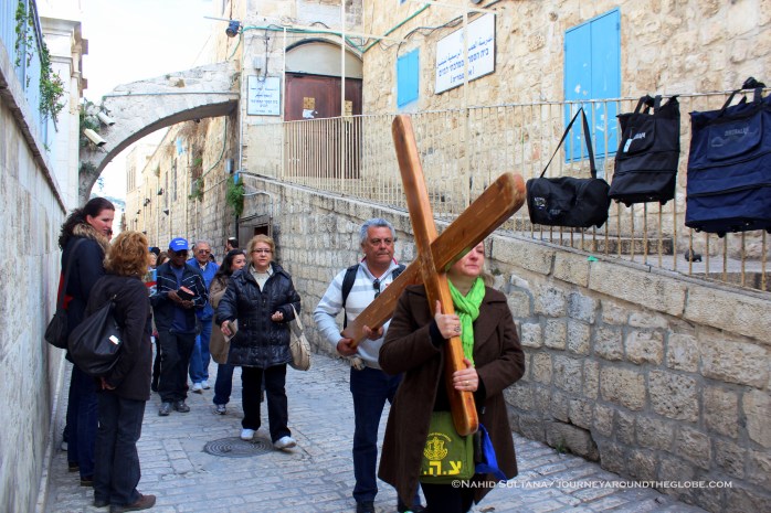 A group of believers walking the "Way of Sorrow" or Via Dolorosa with a cross to comemorate the sufferings of Jesus near 1st station in Old Jerusalem