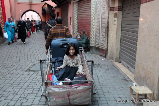 My daughter is being hauled in a luggage cart toward our riad, in Medina, Marrakech