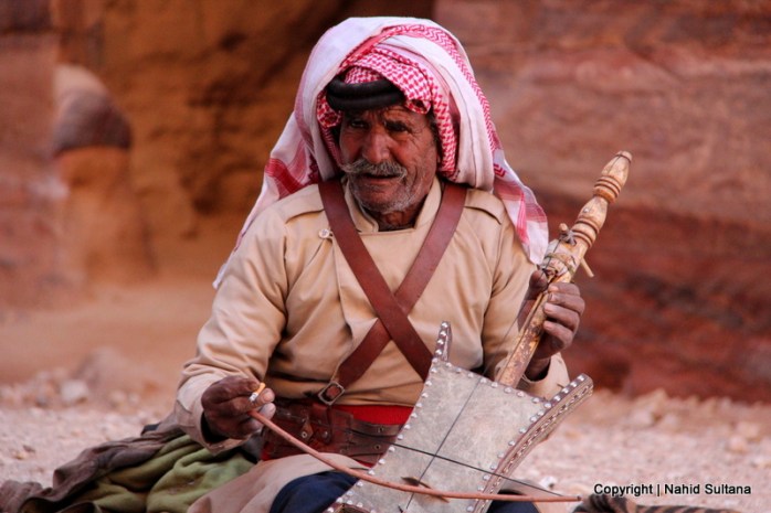 Man playing a very old instrument, called Rebabh, near Khazana in Petra, Jordan