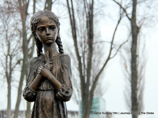 A starving little girl in front of Famine Monument in Kiev, Ukraine